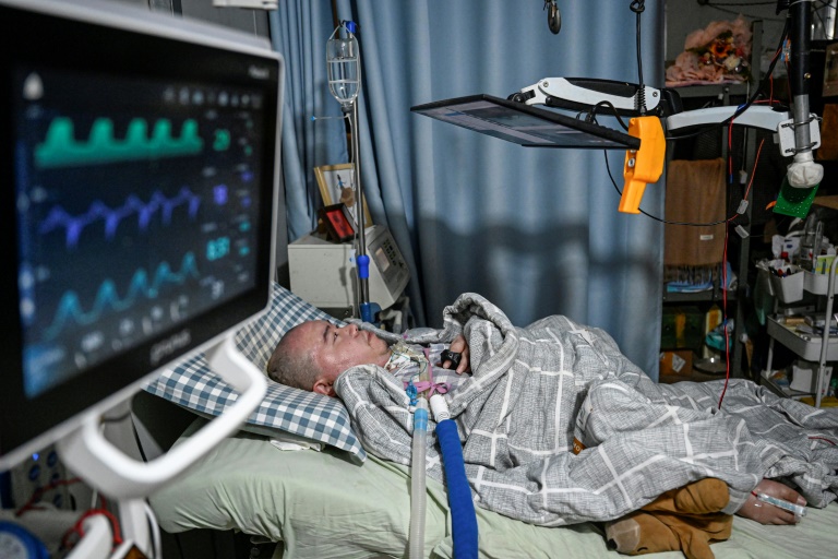 Li Xia, tétraplégique en raison d'une maladie rare, dans son lit sous l'écran qu'il utilise pour diriger sa ferme à distance, à Chongqing, en Chine, le 16 décembre 2025