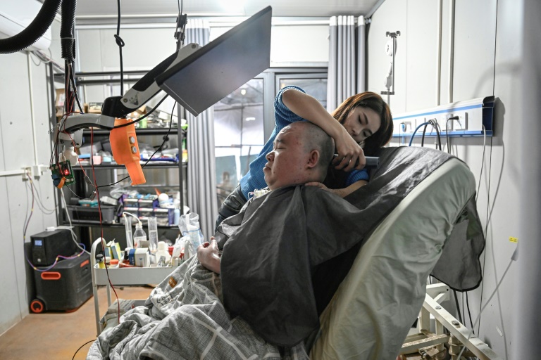 Li Xia, tétraplégique, est aidé par sa soeur Li Qian, chez eux, à Chongqing, en Chine, le 16 décembre 2025