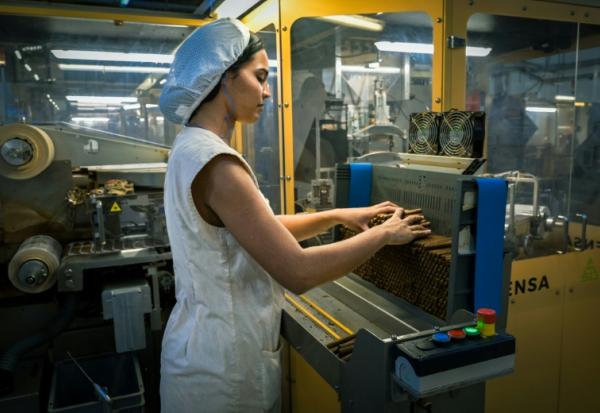 Une ouvrière travaille sur une machine pour confectionner des cigarillos dans l'usine ICT de La havane, le 8 mai 2025