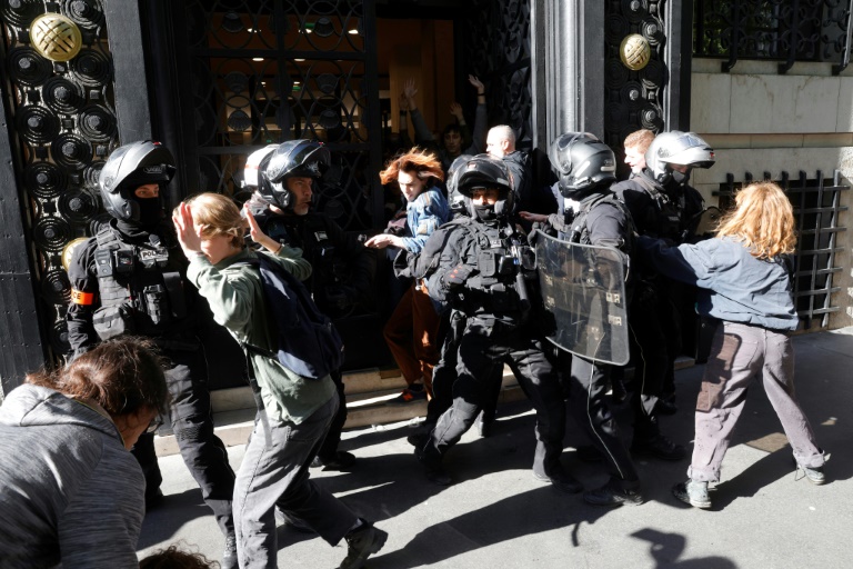 Des policiers repoussent des membres d'Extinction Rebellion (XR) lors d'une manifestation devant les bureaux de la banque BNP Paribas, avant l'assemblée générale ordinaire et extraordinaire des actionnaires de TotalEnergies, le 23 mai 2025 à Paris
