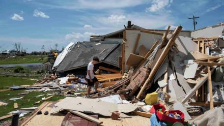 Un jeune garçon marche dans les décombres de sa maison à London, dans le Kentucky, le 17 mai 2025