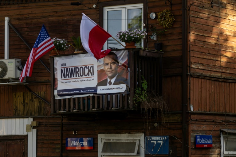 Une affiche électorale de Karol Nawrocki, candidat à l'élection présidentielle, soutenu par le parti de droite polonais Droit et Justice (PiS), exposée sur un balcon à côté des drapeaux polonais et américain, le 6 mai 2025 à Varsovie