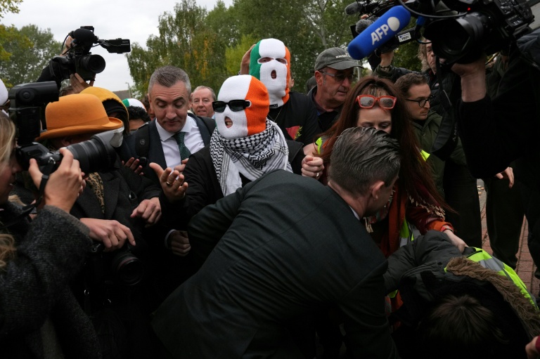 Les membres du groupe Kneecap, dont le chanteur Liam O'Hanna, alias Mo Chara, portent des cagoules aux couleurs du drapeau irlandais à leur arrivée au tribunal de Woolwich, à Londres, le 26 septembre 2025