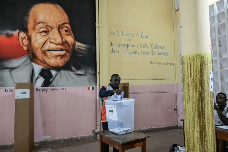 Un représentant de la commission électorale compte les votes de la présidentielle ivoirienne devant un tableau du premier président de Côte d'Ivoire, Félix Houphouët-Boigny, le 25 octobre 2025 à Abidjan