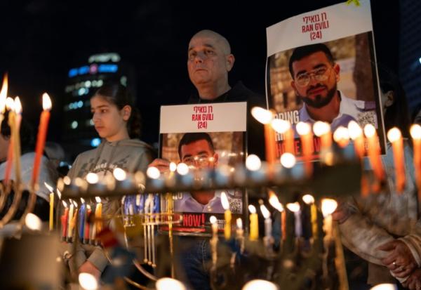 Des Israéliens portent des portraits de Ran Gvili lors de la fête juive d'Hanouka, à Tel Aviv le 21 décembre 2025