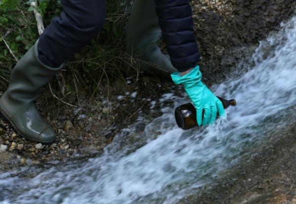 Un bénévole d'une association écologique prélève des échantillons d'eau dans les rejets d'une usine fabriqunate des molécules de type PFAS pour les industries pharmaceutique et des pesticides, le 18 avril 2024 à Salindres, dans le Gard 