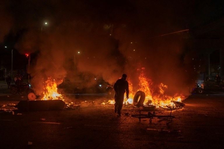 Un homme jette un pneu dans un feu lors d'affrontements avec la police, alors que des manifestants protestent contre les résultats préliminaires du second tour de l'élection présidentielle à Bogotá, en Colombie, le 21 juin 2026