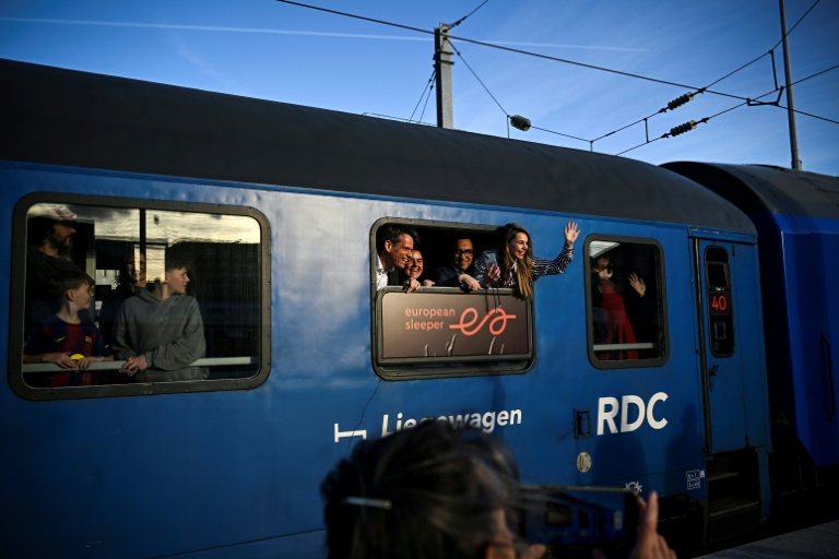Des passagers saluent les journalistes depuis un wagon du premier train de nuit de la ligne Paris-Berlin gérée par la compagnie néerlando-belge European Sleeper, au départ de la Gare du Nord à Paris, le 26 mars 2026