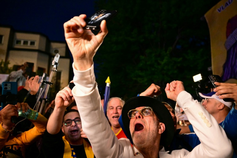 Des partisans du chef du parti AUR George Simion saluent sa victoire au premier tour de la présidentielle, le 4 mai 2025 à Bucarest