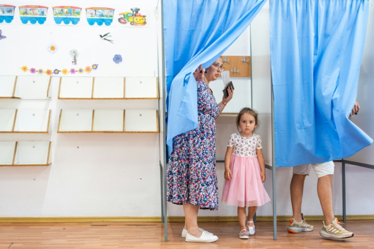 Une femme vote avec sa fille pour la présidentielle roumaine, le 4 mai 2025 à Ciocanesti