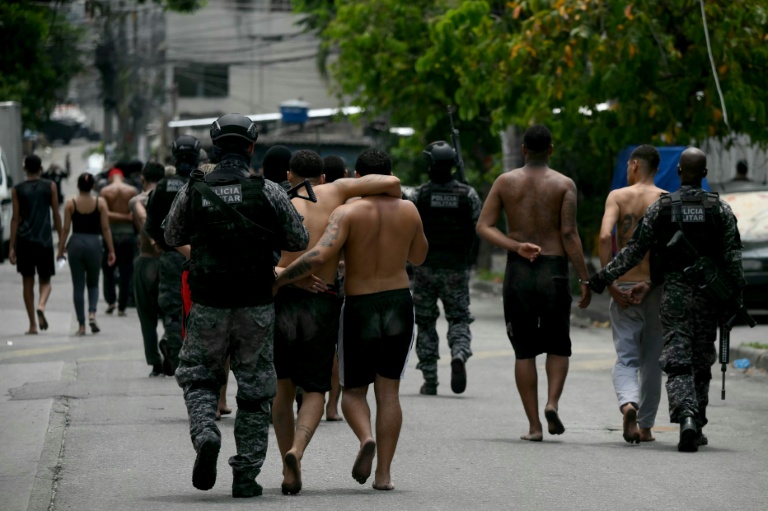 Des policiers escortent des criminels présumés arrêtés lors d'une opération dans la favela de Vila Cruzeiro, dans le complexe de Penha, à Rio de Janeiro, le 28 octobre 2025 au Brésil