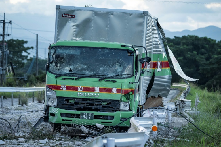 Un camion endommagé est laissé sur une route jonchée de débris à la suite d'une explosion survenue au centre commercial Aeon Mall à Kumamoto, à Kashima, dans le sud du Japon, le 29 juillet 2026, après qu'un tremblement de terre a frappé la région