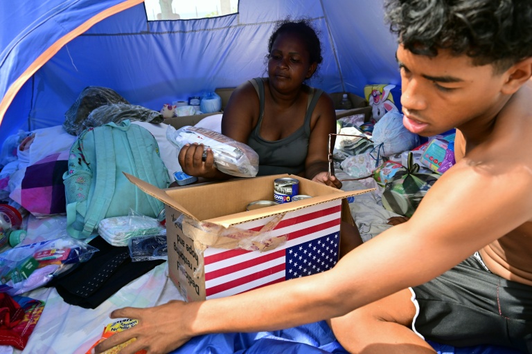 Des habitants déplacés le double séisme du 24 juin reçoivent un carton d'aide humanitaire américaine dans un centre d'accueil à Catia La Mar, dans l'Etat de La Guaira, au Venezuela, le 8 juillet 2026