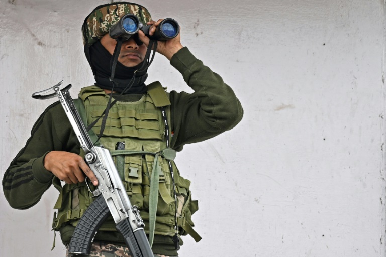 Un membre du personnel paramilitaire indien assure une surveillance à l'aide de jumelle en haut d'un bâtiment commercial à Srinagar, le 5 mai 2025 au Cachemire indien