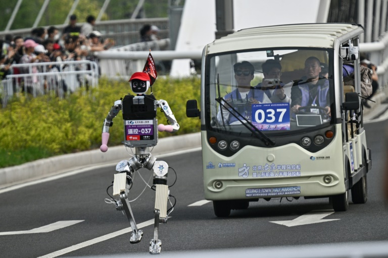 Un robot suivi par une équipe d'ingénieurs, participe au semi-marathon de Yizhuang, dans la banlieue de Pékin, le 19 avril 2026