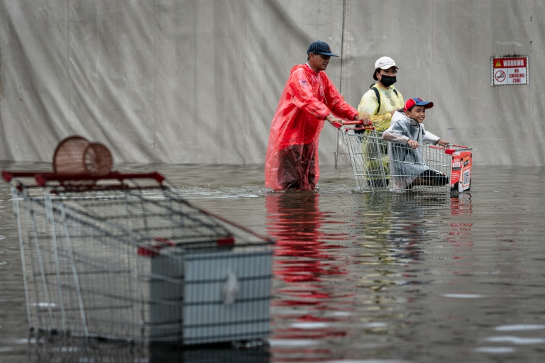 Des habitants dans une rue de Bangkok, où l'état de catastrophe naturelle a été déclaré après des pluies diluviennes qui ont inondé habitations, commerces et axes de circulation, le 27 septembre 2026