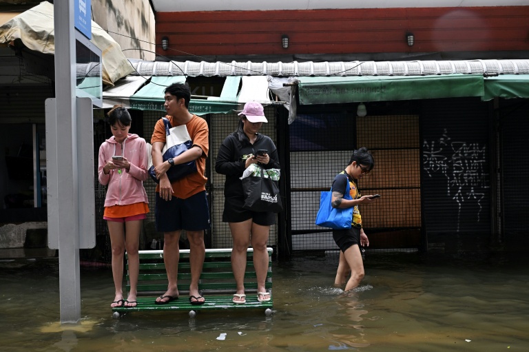 Des habitants sur un banc dans une rue de Bangkok, où l'état de catastrophe naturelle a été déclaré après des pluies diluviennes qui ont inondé habitations, commerces et axes de circulation, le 27 septembre 2026