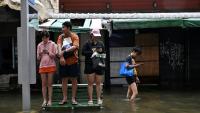 Des habitants sur un banc dans une rue de Bangkok, où l'état de catastrophe naturelle a été déclaré après des pluies diluviennes qui ont inondé habitations, commerces et axes de circulation, le 27 septembre 2026