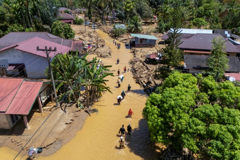 Cette photo aérienne montre des villageois pataugeant dans la coulée de boue pour trouver un abri après les crues soudaines du village de Tukka, dans le district de Tapanuli central, province de Sumatra du Nord, le 3 décembre 2025
