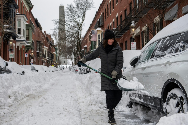 Une femme déneige la route à Boston, le 26 janvier 2026 dans le Massachusetts