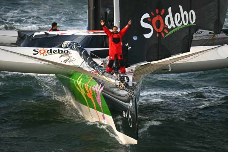 Thomas Coville célèbre son record du tour du monde à la voile (Trophée Jules Verne) dimanche matin quelques instants après avoir passé la ligne d'arrivée au large de Brest avec son équipage sur Sodebo Ultim.