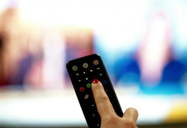 Une personne tient une télécommande pointée vers un écran de télévision, à Paris le 15 janvier 2025
