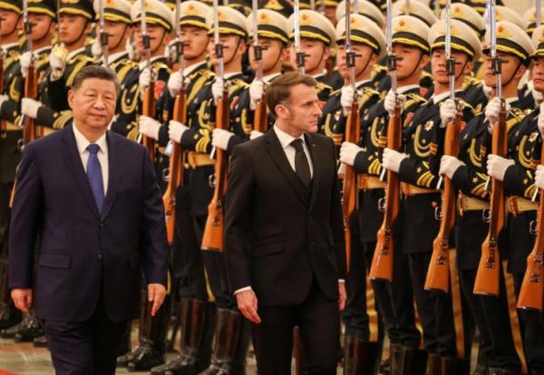 Le président chinois Xi Jinping (à gauche) et le président français Emmanuel Macron (à droite) passent en revue la garde d'honneur lors d'une cérémonie de bienvenue au Palais du Peuple à Pékin, le 4 décembre 2025