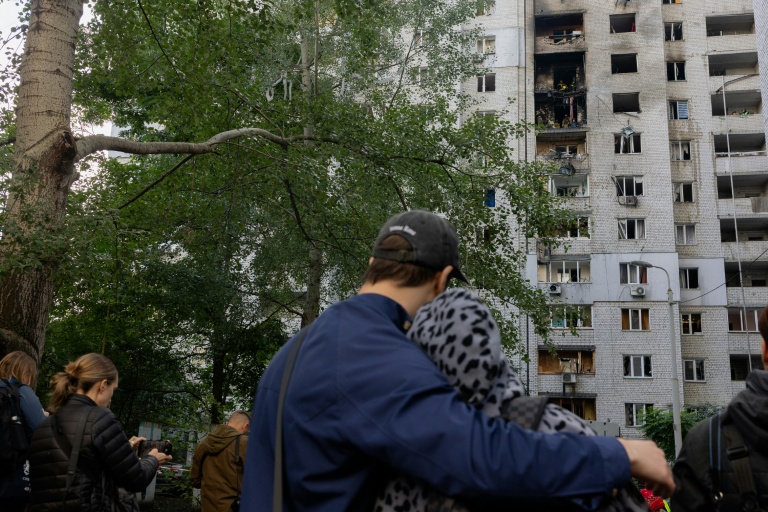 Des habitants observent un immeuble résidentiel endommagé après une frappe de drone russe à Kiev, le 25 septembre 2026