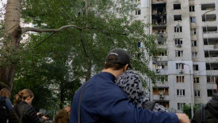 Des habitants observent un immeuble résidentiel endommagé après une frappe de drone russe à Kiev, le 25 septembre 2026