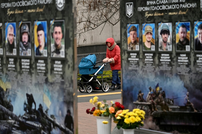 Une femme et son enfant tarversent un site en mémoire aux combattants ukrainiens tombés face aux troupes russes, à Kiev, le 7 décembre 2025