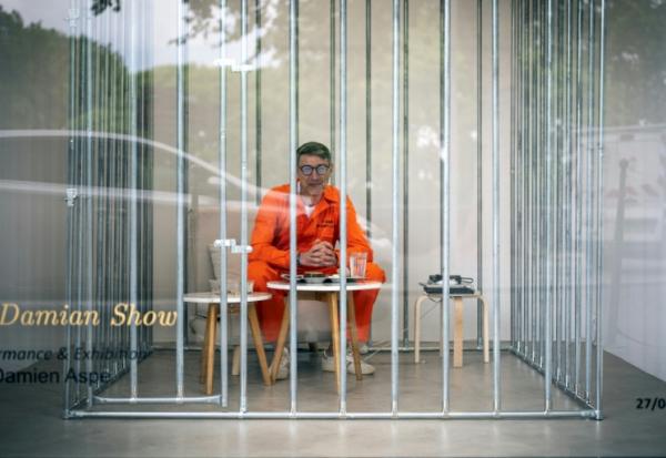 L'artiste Damien Aspe visible à travers la vitrine de sa galerie, où il s'est enfermé dans une cage pour dénoncer l'emprise des GAFAM, le 28 avril 2028 à Toulouse