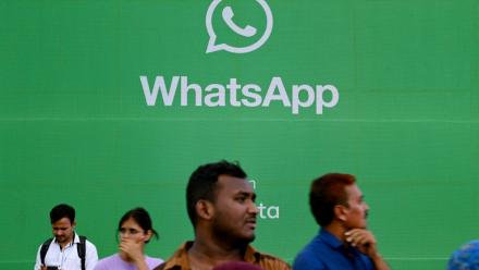Des touristes devant une publicité pour l'application de messagerie Whatsapp, à Bombay le 25 août 2023