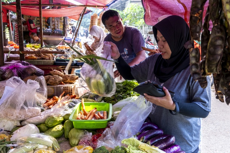 Une cliente (d) achète des légumes sur un étal d'un marché à Jakarta, le 3 juin 2026 en Indonésie