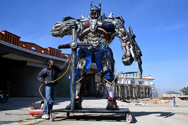 Le sculpteur Ehtisham Jadoon à côté de son Optimus Prime, personnage du film Transformers, fabriqué à partir de ferraille devant son atelier situé à la périphérie d'Islamabad, le 12 février 2026 au Pakistan