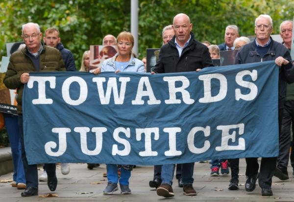 Des proches des victimes du "Bloody Sunday" brandissent une banderole sur laquelle est écrit "Towards Justice" (En faveur de la justice) alors qu'ils se rendent à pied au tribunal de Belfast, en Irlande du Nord, le 16 octobre 2025
