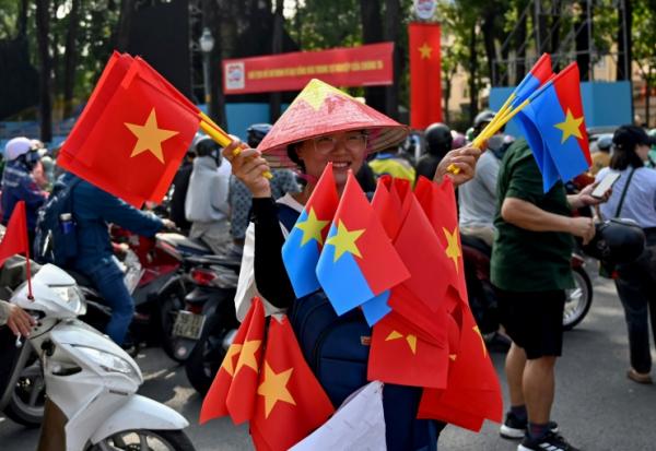 Une vendeuse de drapeaux vietnamiens et de l'armée Viet Cong, le 29 avril 2025 à Ho Chi Minh Ville
