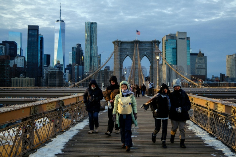 Des passants bravent le froid en traversant le pont de Brooklyn, dans le quartier de Manhattan à New York, le 21 janvier 2026
