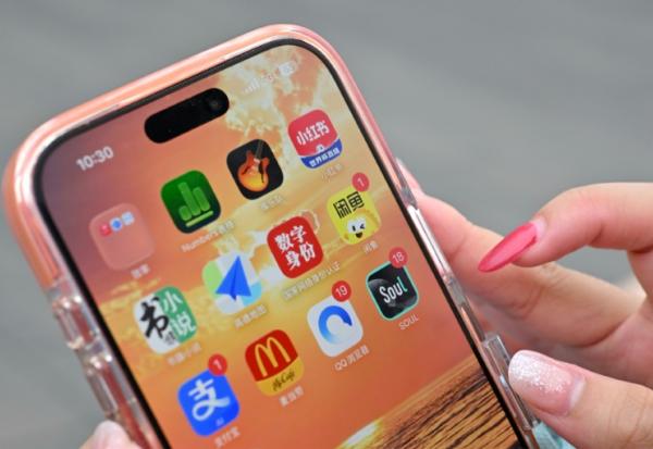 Une utilisatrice de Xiaohongshu se prépare à ouvrir l'application chinoise (en haut à droite) alors qu'elle visite la Cité interdite à Pékin, le 11 juillet 2026